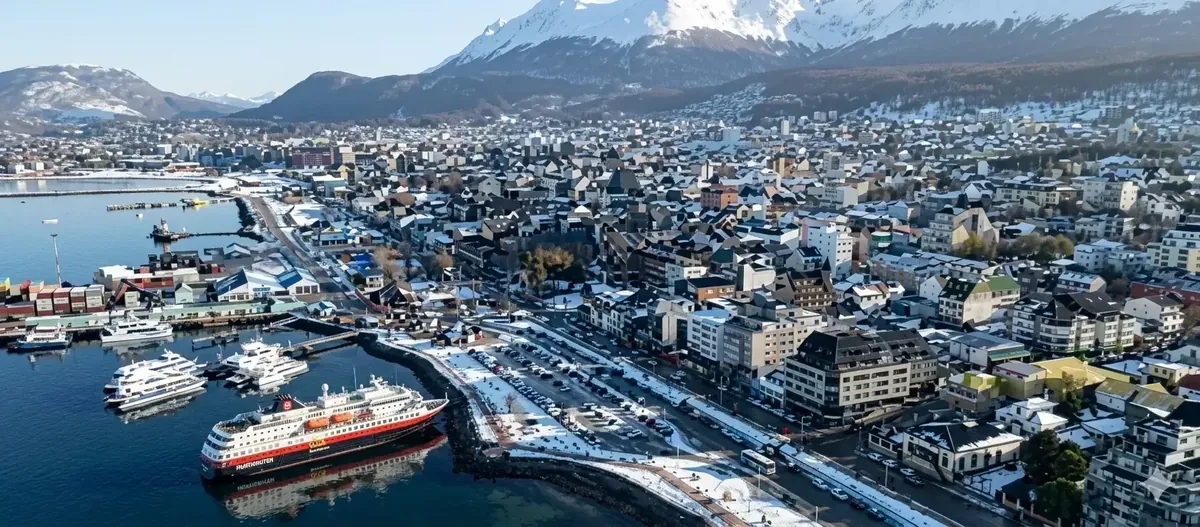 Vista aérea de Ushuaia nevada con el puerto, cruceros y montañas nevadas al fondo